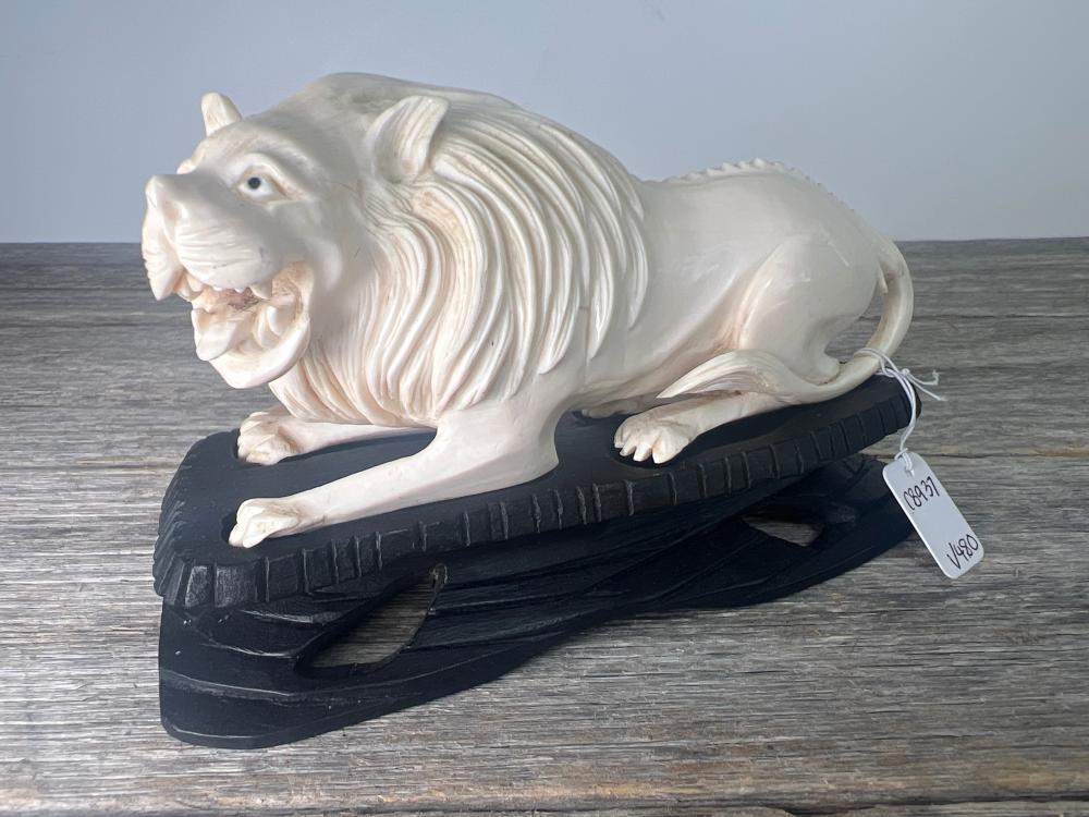 Carved ivory figure of a recumbent lion on stand, Earlier 20th century
