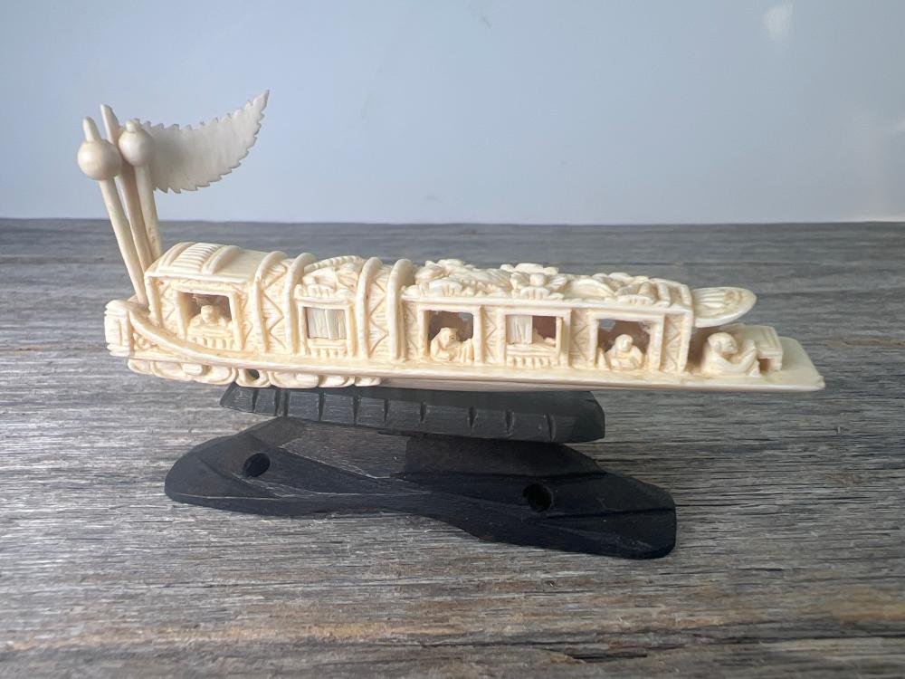 Chinese carved ivory model junk, thedeckhouse with pierced fenestration enclosing seated figures, prow with phoenix finial, on carved hardwood stand, early 20th century