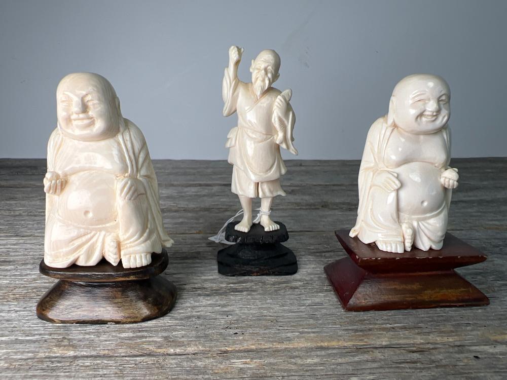 Group of three Chinese carved ivory figures, comprising two Budai and a fisherman, on wooden stands, early to mid 20th century