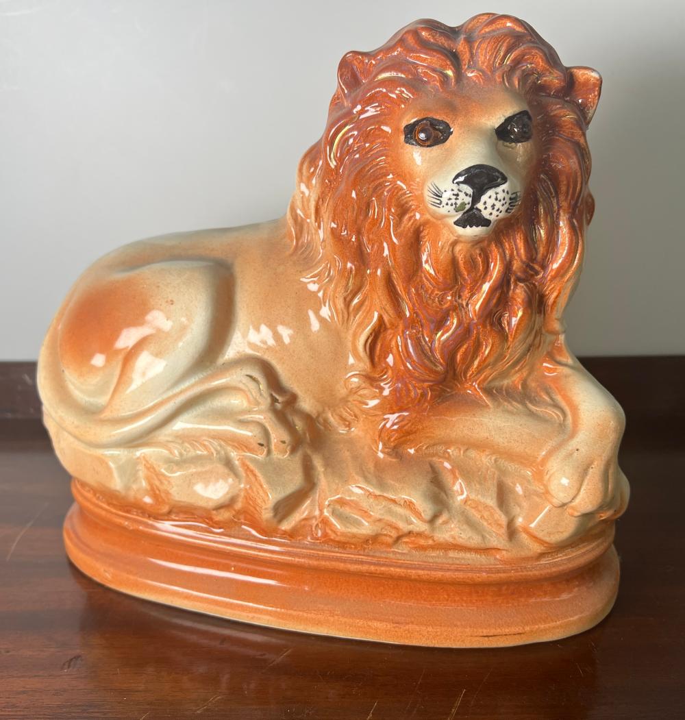 Staffordshire-style pottery recumbent lion, ochre and cream glaze, oval base, circa 1860–1900