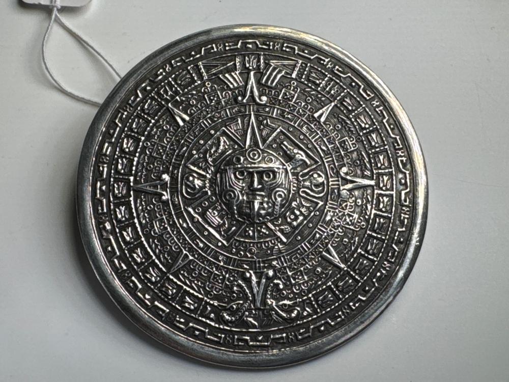 Mexican silver circular brooch, depicting stylised Aztec motifs in relief, mid-20th century